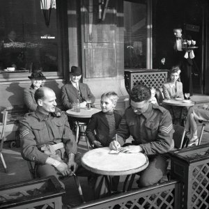 Two Canadian soldiers signing the autograph book of a young Belgian boy in Antwerp, Belgium in 1944.