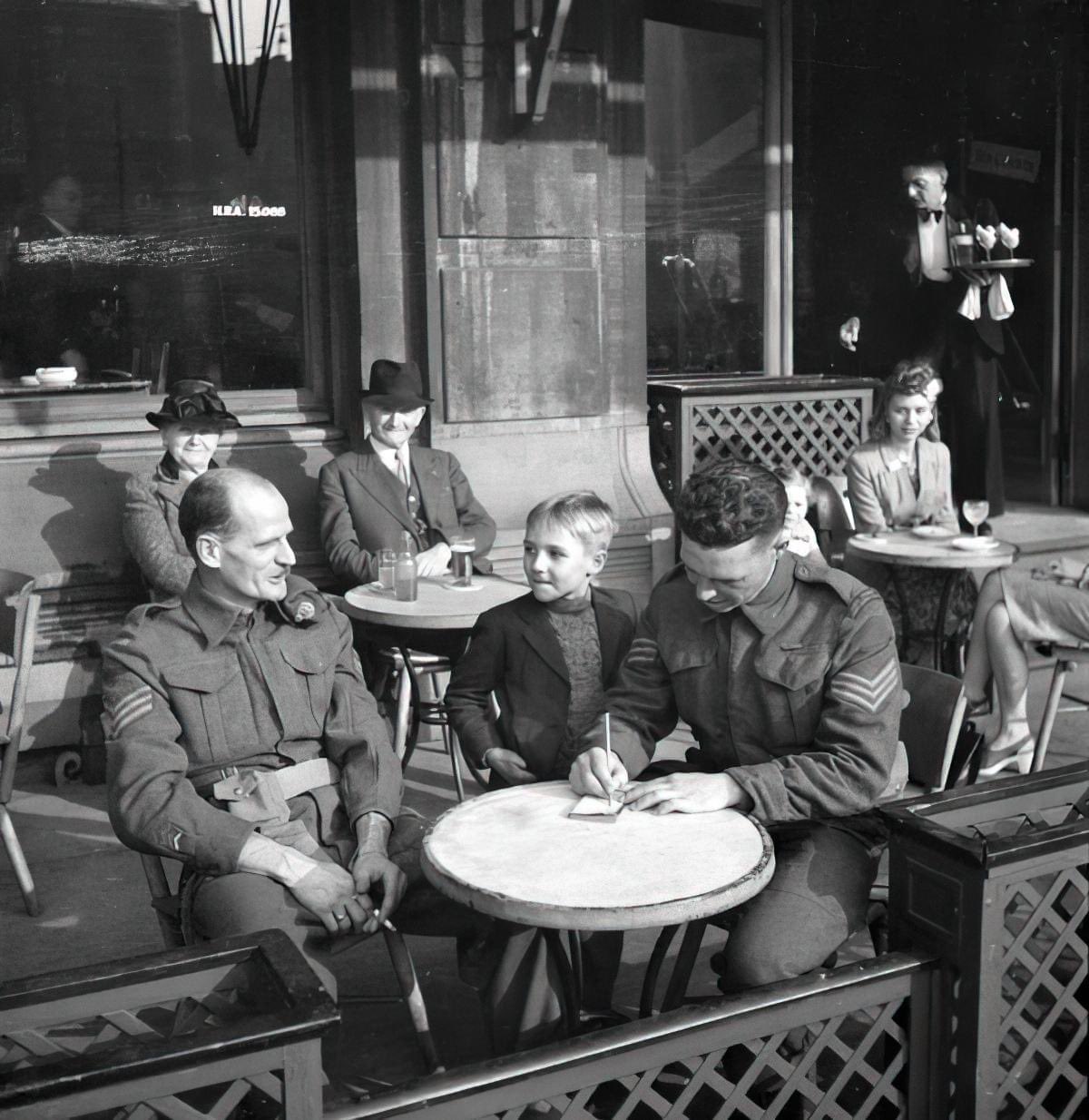 Two Canadian soldiers signing the autograph book of a young Belgian boy in Antwerp, Belgium in 1944.